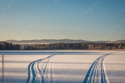 Photos traces of a snowmobile in the fresh snow on a frozen lake