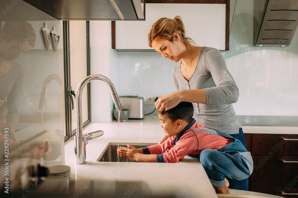 Caring mother and kid wash hands in a sink Caring mother and kid wash hands in a sink