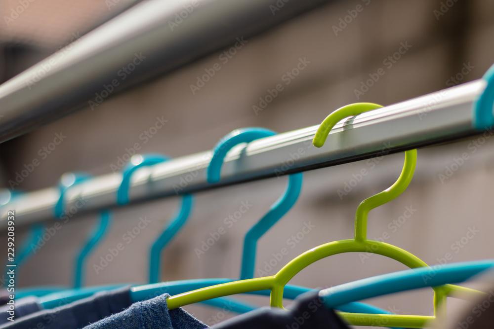 Green hanger Plastic In the clothes array with a blue hanger Plastic.