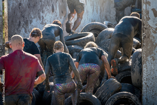 Athletes climbing over car tires at an obstacle course race 