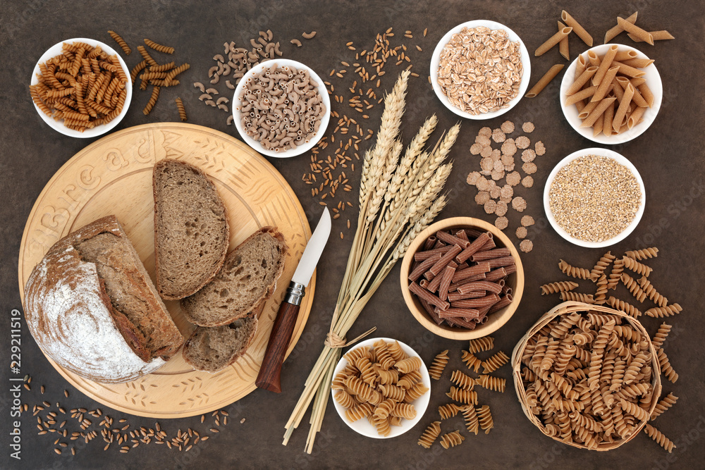 High fibre natural health food with whole wheat pasta, whole grain rye bread, oatmeal, oats, bran flakes and wheat sheath on lokta paper background. 