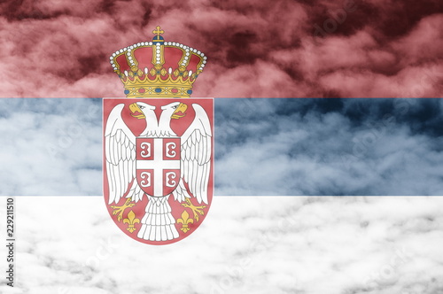Obraz na plátně Serbian flag with cloud sky background.