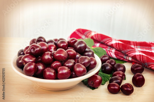 Fresh ripe sweet cherry in a plate on a light table photo