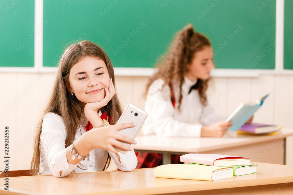 schoolgirls in school uniforms sit for couples in the classroom. Girls go to school.