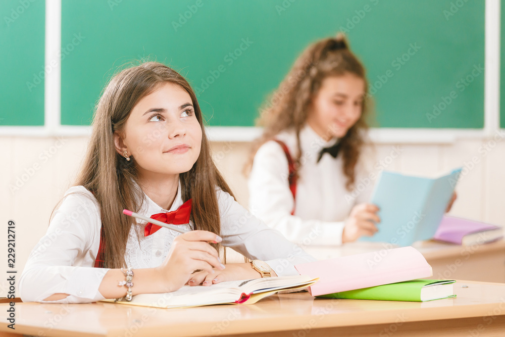 schoolgirls in school uniforms sit for couples in the classroom. Girls go to school.