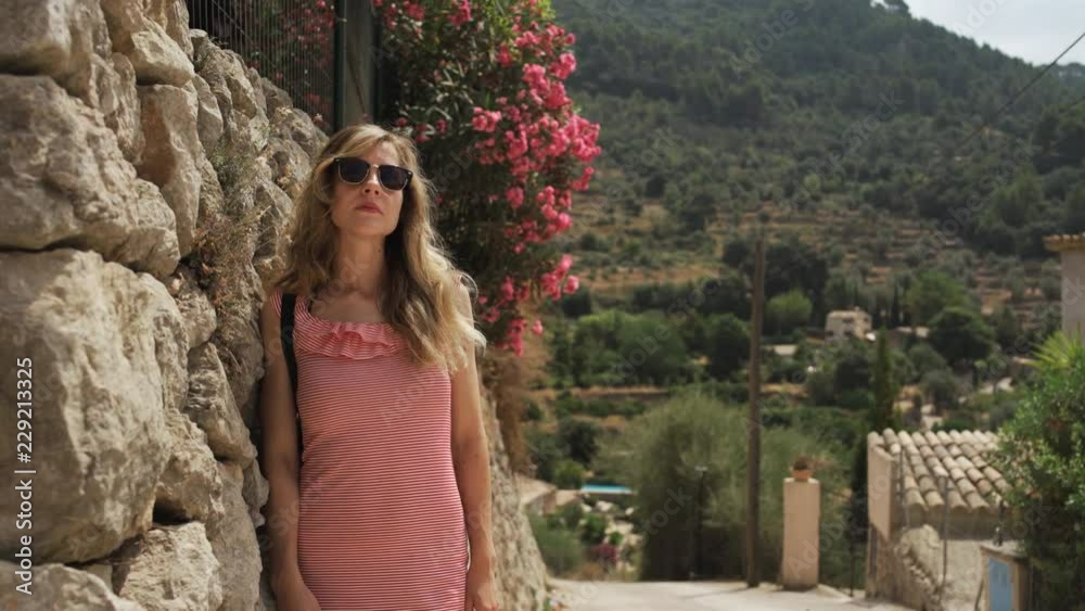 Woman stands by flowers in old town of Valldemossa, Mallorca Woman stands by flowers in old town of Valldemossa, Mallorca