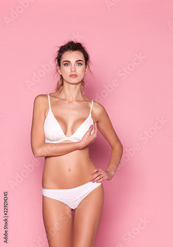 Beautiful woman in white lingerie on a pink background