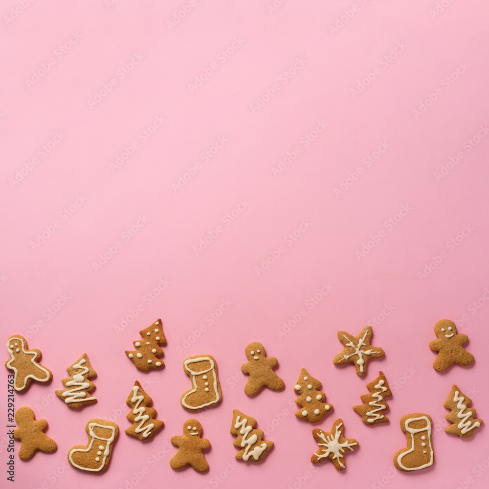 Homemade christmas cookies on pink background with copy space. Square crop. Pattern of gingerbread men, snowflake, star, fir-tree, boot shapes. New year concept