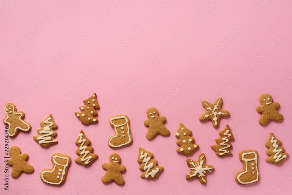 Christmas handmade cookies on pink background with copy space. Pattern of gingerbread men, snowflake, star, fir-tree, boot shapes. New year concept