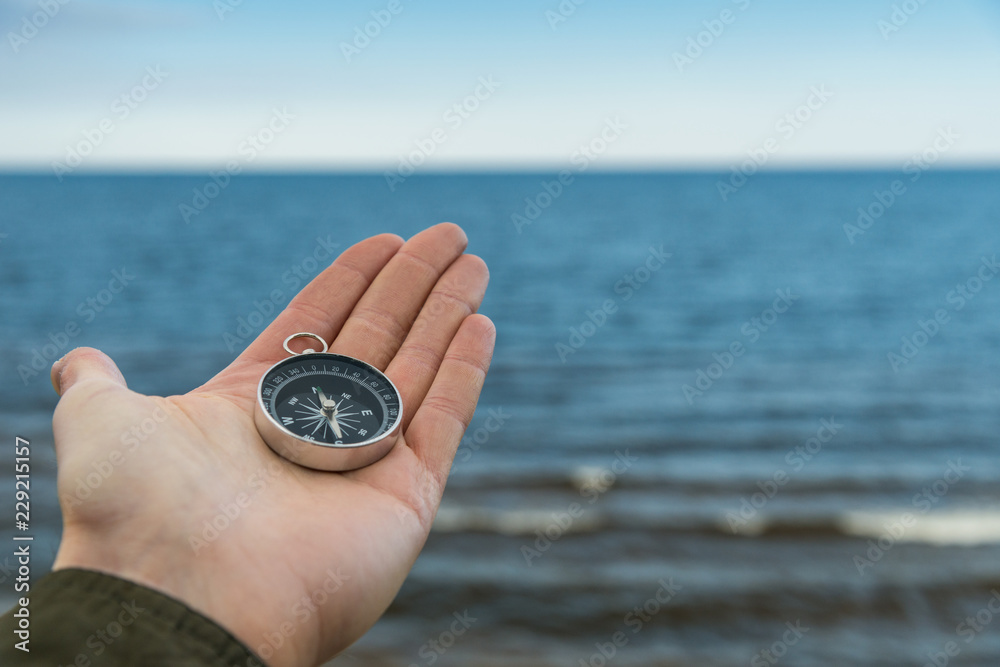 Traveler holding compass against blue water