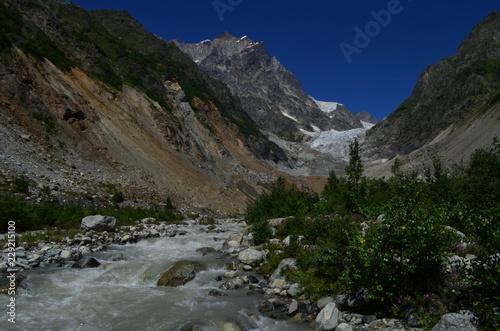 view of the glacier with river in the foreground and clear blue sky