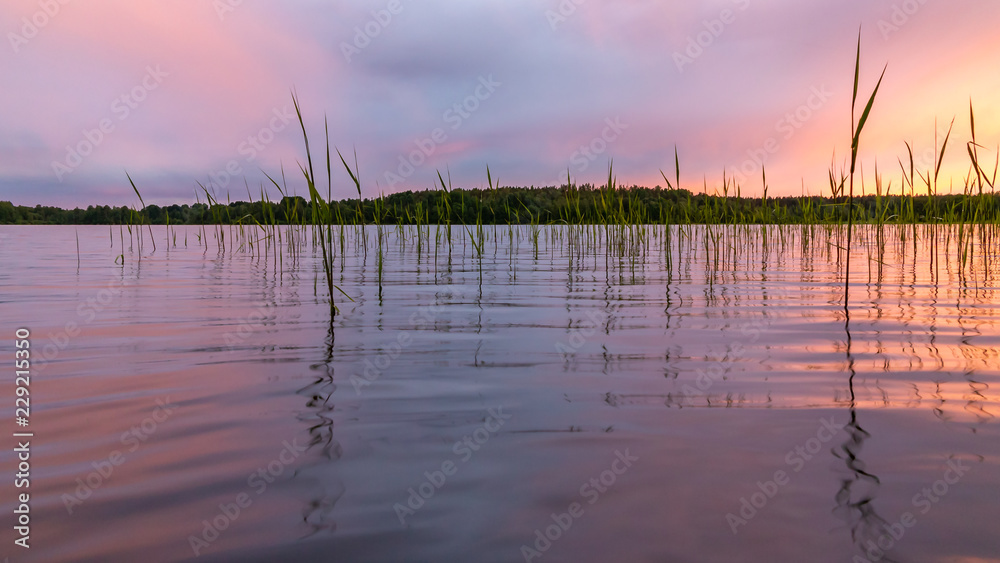 Reflected in the smooth water of the lake clouds at sunset. Colorful landscape, background blur Reflected in the smooth water of the lake clouds at sunset. Colorful landscape, background blur
