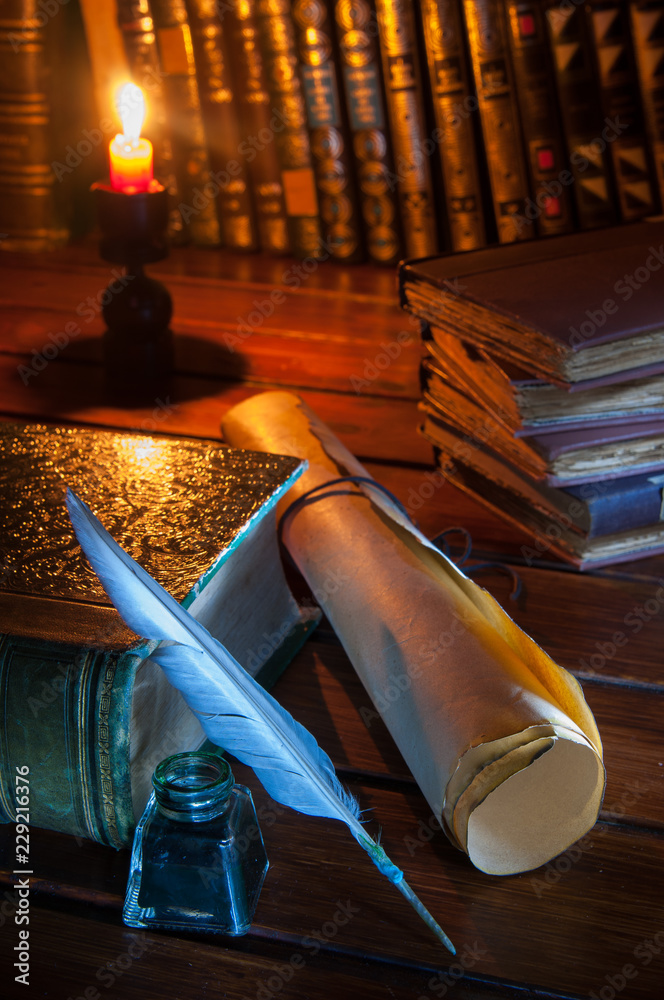 Quill pen and a rolled papyrus sheet on a wooden table with old books