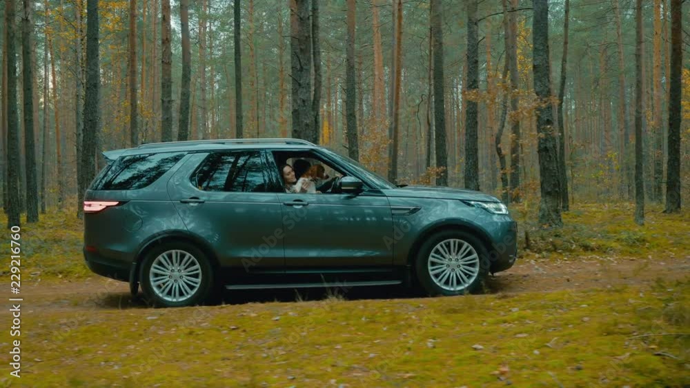 TRACKING Caucasian couple with a pet dog driving on a forest road in a modern SUV. 4K UHD TRACKING Caucasian couple with a pet dog driving on a forest road in a modern SUV. 4K UHD