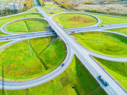 Aerial view of highway in city. Cars crossing interchange overpass. Highway interchange with traffic. Aerial bird's eye photo of highway. Expressway. Road junctions. Car passing. Top view from above. © Aleksei