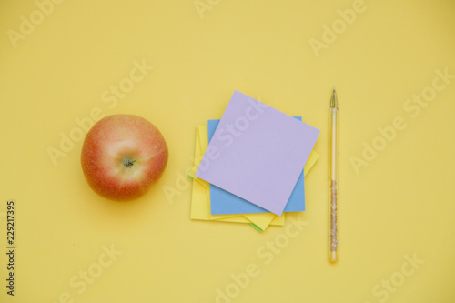 pen and Apple stickers on yellow background with copy space top view