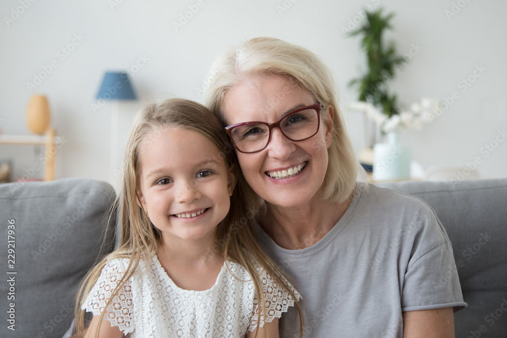 Portrait of smiling cute little girl posing with grandma hugging and ...
