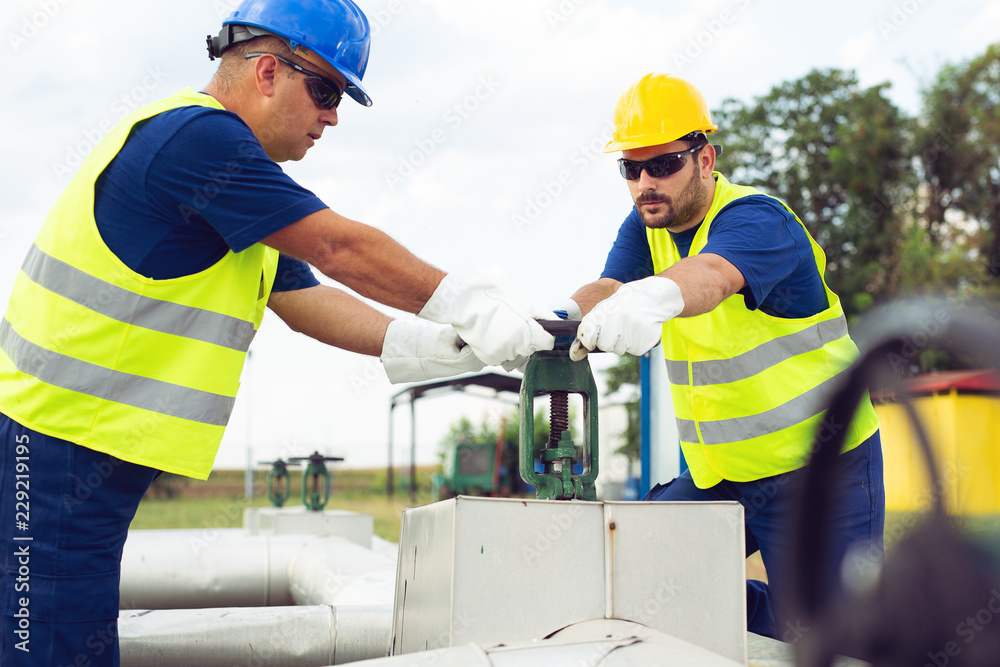 Oil worker closes the valve on the oil pipeline Oil worker closes the valve on the oil pipeline
