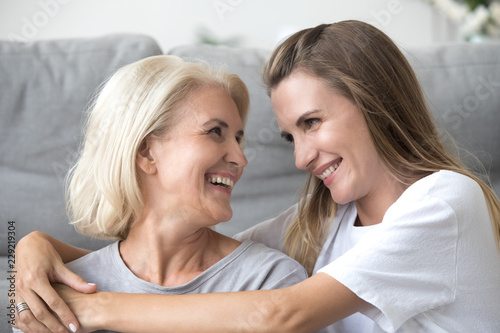 Konstfotografi Happy elderly mother and millennial daughter hug looking in eyes enjoying sweet