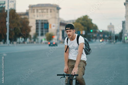 Man riding bicycle in urban city holding hands on handlebar