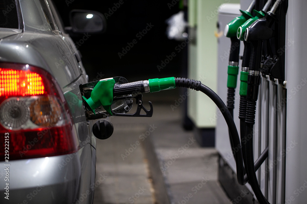 Fuelling gun inserted into the tank of gray car Fuelling gun inserted into the tank of gray car