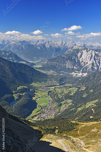 View from the summit of Acherkogel mountain  Tyrol  Austria  at a beautiful day to the Inn and Oetztal valley with the village of Oetz. Alpine landscape with rocky mountains  pastures  blue sky.