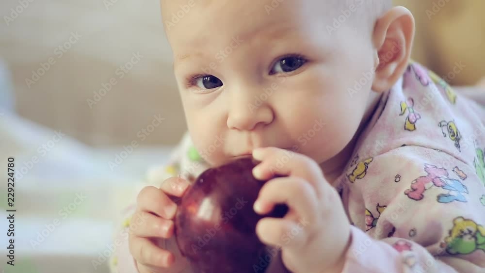 newborn baby lying on the bed and eating an Apple newborn baby lying on the bed and eating an Apple