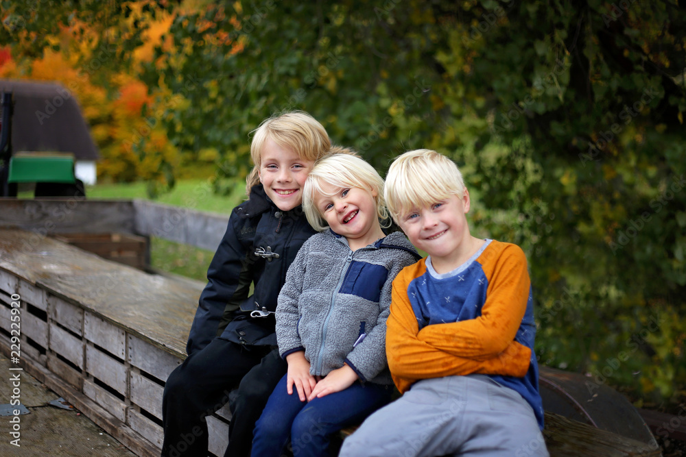 Three Cute Kids Bundled up Tractor Wagon Ride on Chilly Fall Day Three Cute Kids Bundled up Tractor Wagon Ride on Chilly Fall Day