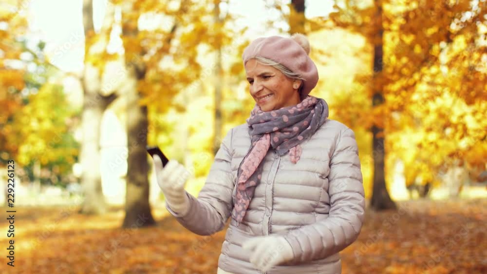 old age, retirement and technology concept - happy senior woman taking selfie by smartphone at autumn park