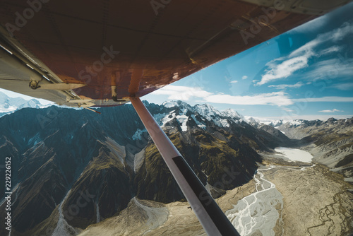 View of snowy mountains under plane wing photo