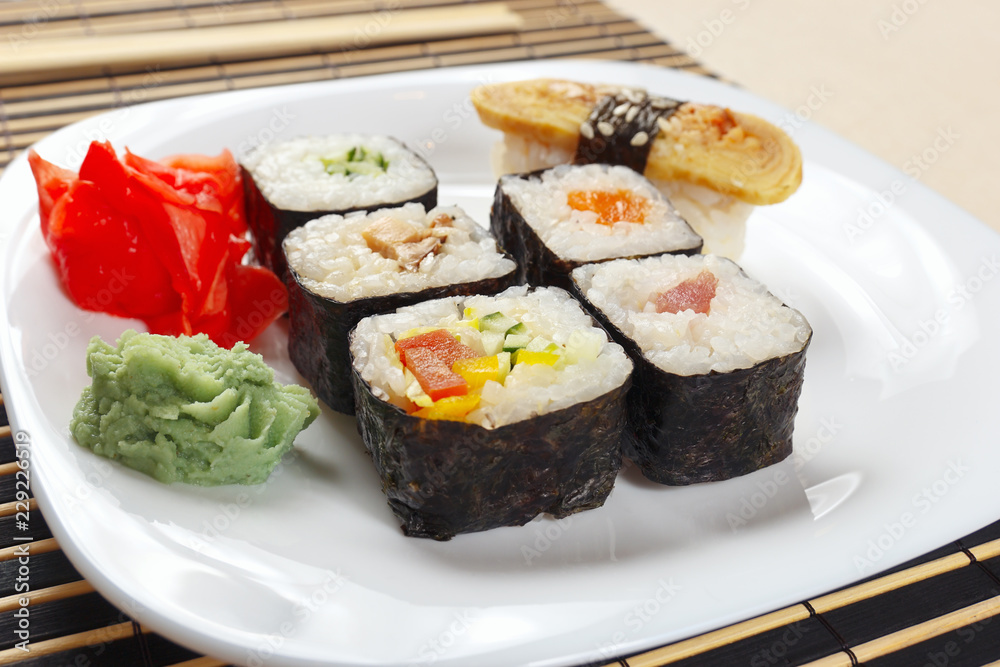 Sushi and rolls with ginger and wasabi on a black bamboo mat close up. Sushi and rolls with ginger and wasabi on a black bamboo mat close up.