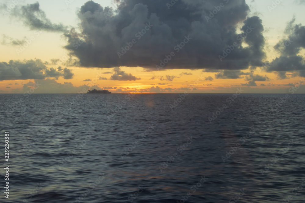 silhouette of a ship at sea traveling under clouds at sunset in the Bahamas