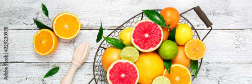 Obraz  z motywem Citrus fruits and cooking citrus juice  on wooden table. Assorted fresh citrus fruits with leaves. Healthy eating, dieting, vegetarian food concept. Long web format. Top view