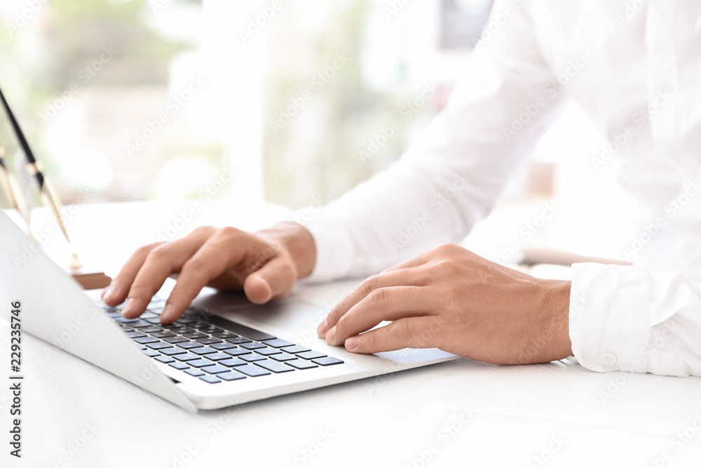 Male notary working with laptop at table in office, closeup Male notary working with laptop at table in office, closeup