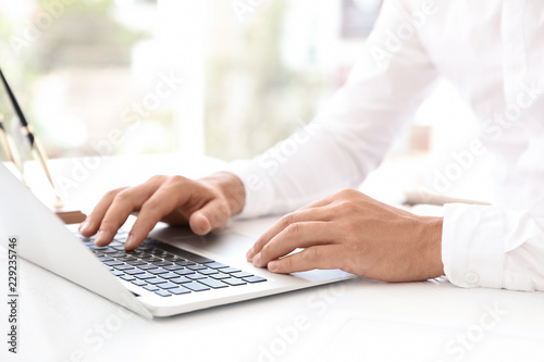 Male notary working with laptop at table in office, closeup