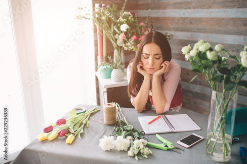 Canvas Print Female florist at work: pretty young dark-haired woman making fashion modern bouquet of different flowers