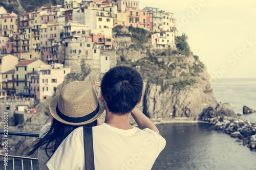 Tourist couple looking at traditional port town embraced in a hug.