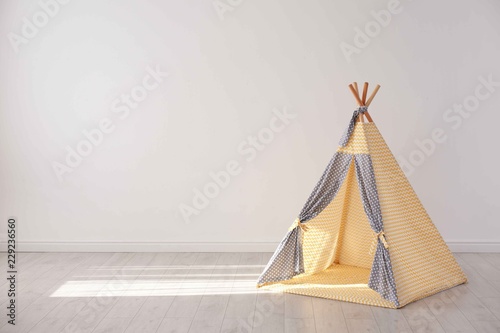 Cozy play tent for kids as element of nursery interior in empty room with space for text