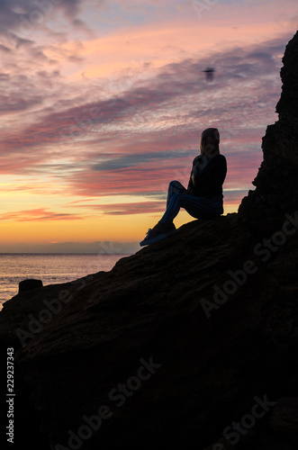 The silhouette of girl that standing on the stone near the sea