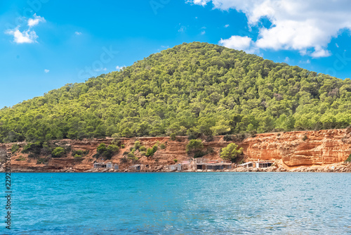 Ibiza, Sa Caleta beach, old fisherman’s sheds on the shore, beautiful red cliffs 
