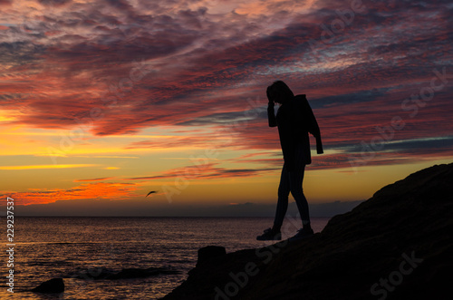 The silhouette of girl that standing on the stone near the sea