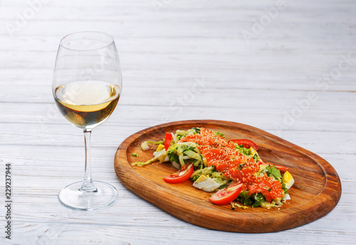 Red fish with sesame on vegetables with a glass of white wine