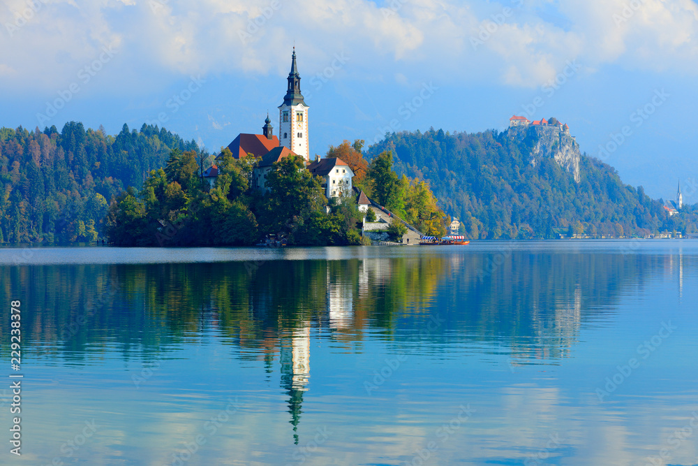 Bled lake island, St Martin Catholic church and Castle with mountain Range, Slovenia, Europe. Landscape in Slovenia, nature in Europe.  Foggy Triglav Alps with forest, travel in Slovenia.