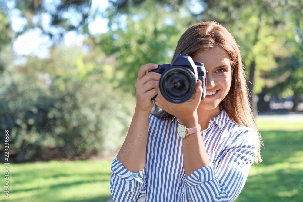 Young female photographer with professional camera in park. Space for text Young female photographer with professional camera in park. Space for text