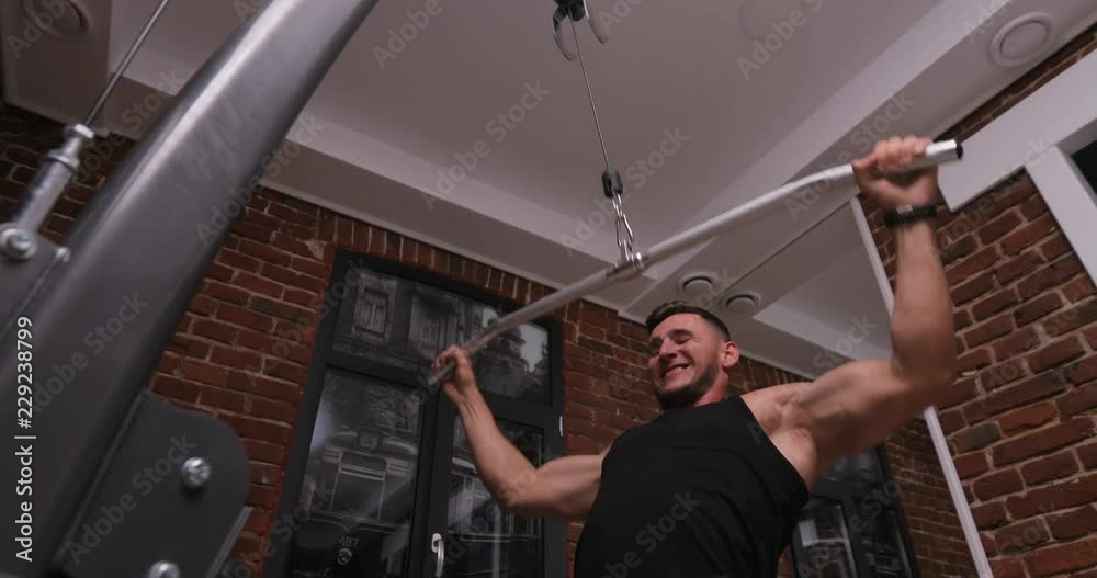 Muscular man doing crossfit training in a dark shadowy gym lifting weights. Health and fitness concept