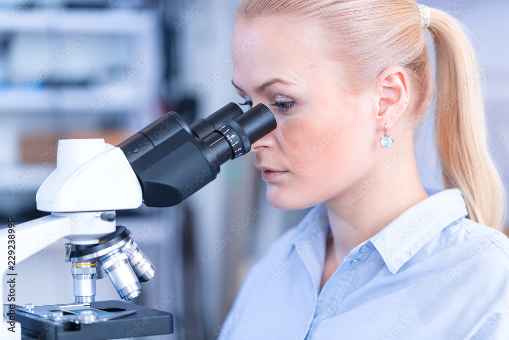Girl with a slide for the microscope University Hospital. Attractive young scientist looking at the microscope slide in the forensic laboratory Girl with a slide for the microscope University Hospital. Attractive young scientist looking at the microscope slide in the forensic laboratory