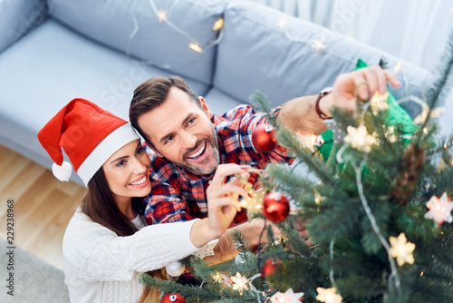Obraz na plátně Portrait of joyful couple decorating christmas tree and spending time together d