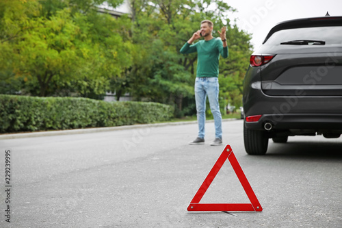 Emergency stop sign and man near broken car on background