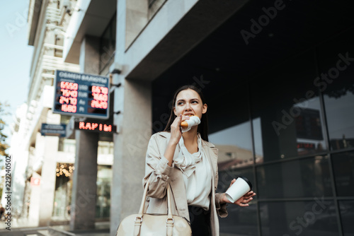 Worker rushes to work and eats on the go, drinks coffee in the street
