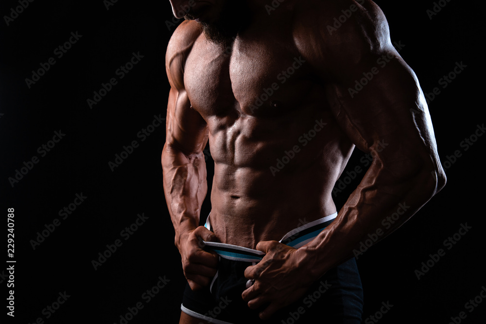 Muscular man's torso on black background with backlight